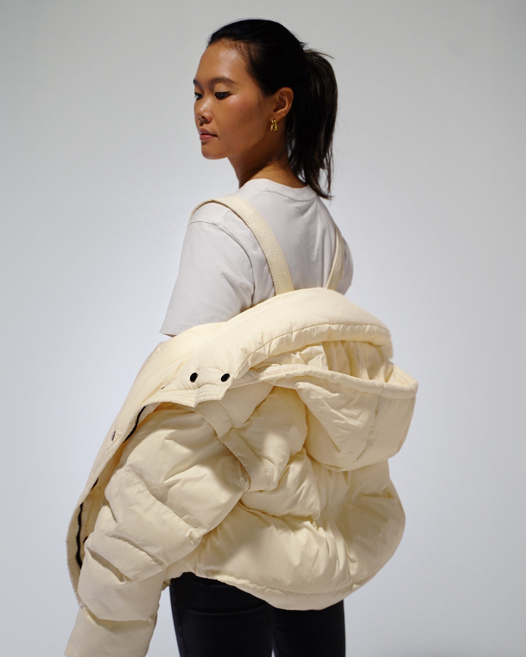 Person wearing a large cream-colored puffer jacket on a plain background
White Wavy streetwear puffer jacket outfit
Model wearing White Wavy convertible puffer jacket
