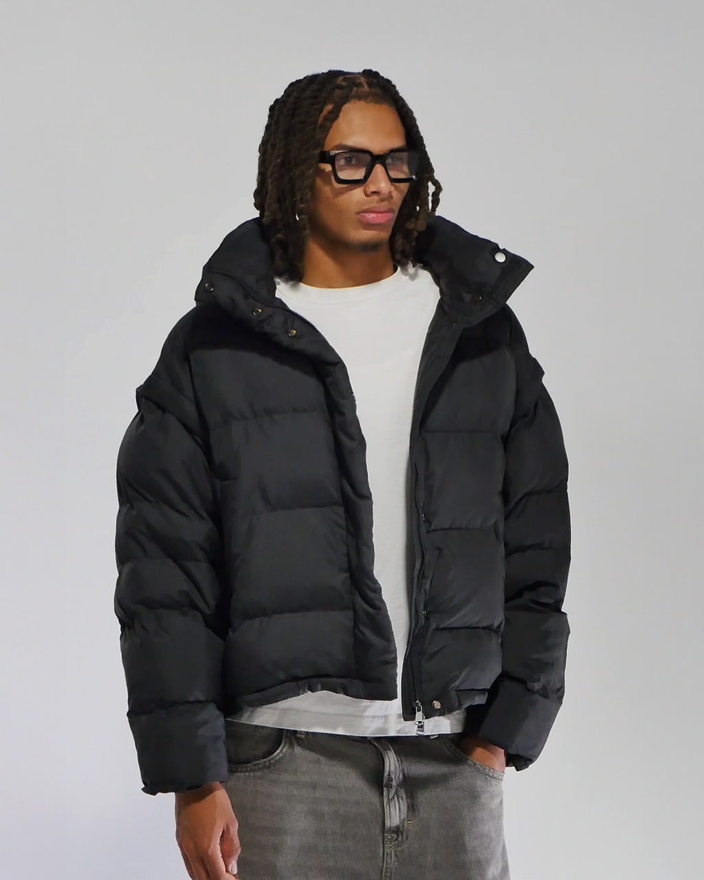 Person wearing a black puffer jacket on a gray background