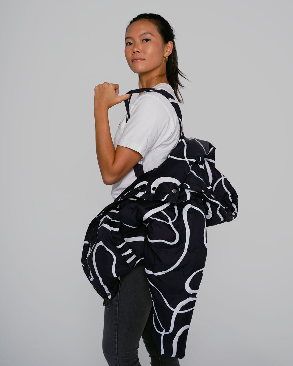 Black Wavy puffer jacket side view with adjustable straps Black Wavy streetwear puffer jacket outfit, Model wearing Black Wavy convertible puffer jacket