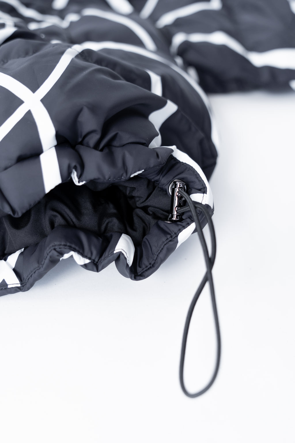 Strap of the black puffer jacket with white patterns on a light background