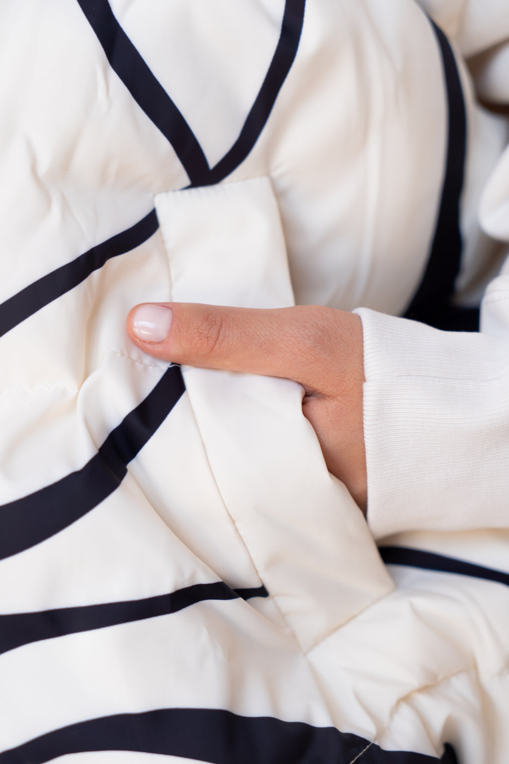 White Wavy puffer jacket with hand in pocket, Model showing White Wavy jacket pocket detail